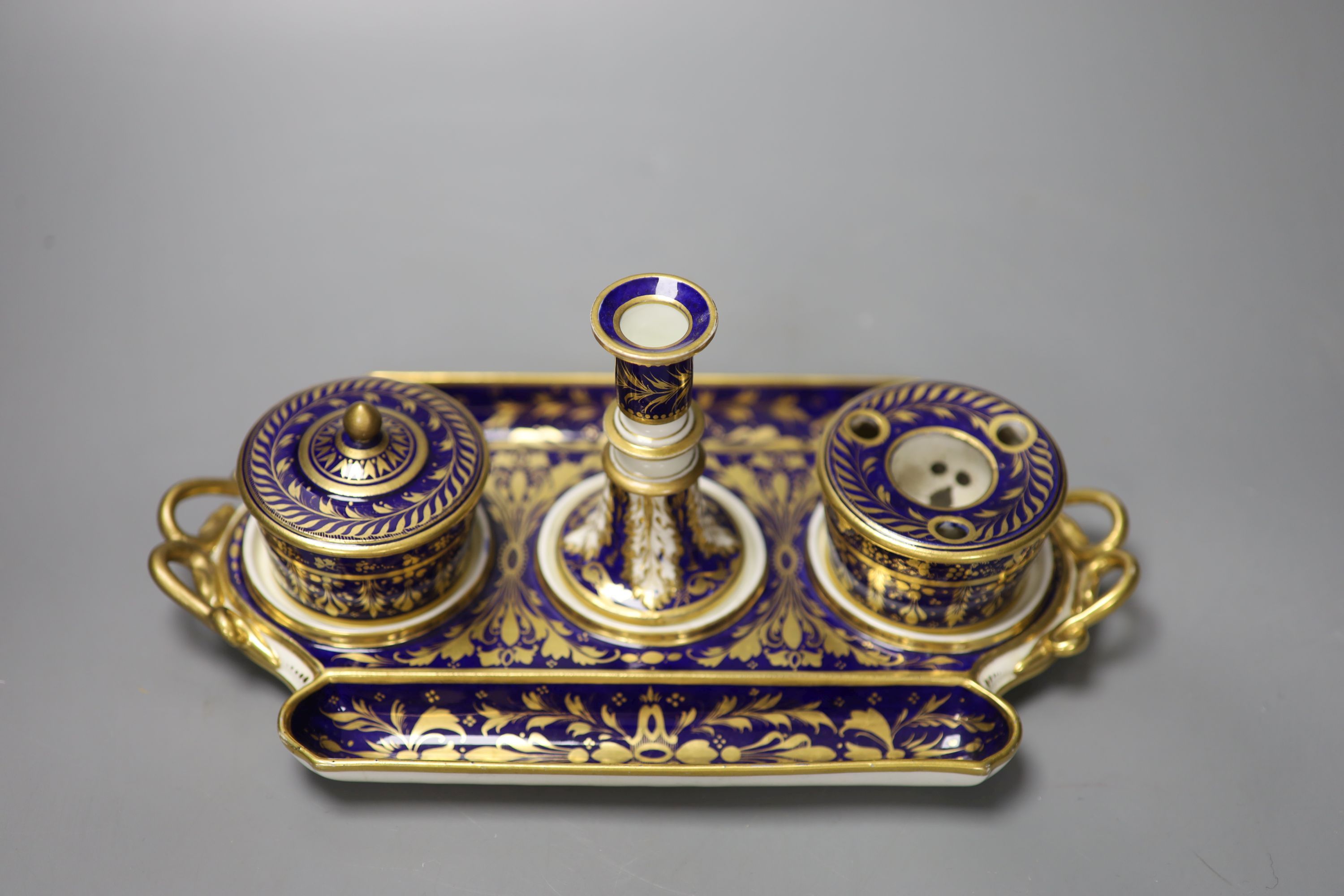 A Derby inkstand ornately gilded on a cobalt blue ground having a sander and cover, inkpot and taper stick, red marks, width 27cm